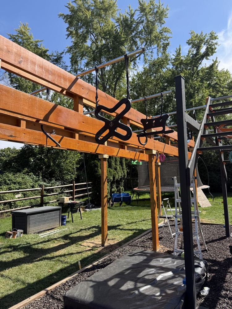 Stained ninja rig loaded with black hanging grips above a crash mat